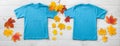 Front and back views on boys t-shirts on white wooden desk background with autumn lievs. Mockup for design closeup Royalty Free Stock Photo