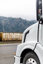 The front of the cab and the hood of modern big rig semi truck parked on parking lot near the warehouse Royalty Free Stock Photo