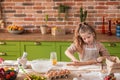 In front of the camera charismatic little girl at the kitchen island take the dough and using the roller preparing her