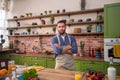 In front of the camera posing guy at the kitchen he looking straight and smiling very charismatic he wear kitchen apron Royalty Free Stock Photo