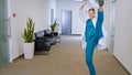 In front of the camera pretty lady doctor in a modern hospital corridor dancing and feeling great she have a cute large Royalty Free Stock Photo