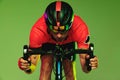 Front camera view of sportsman, cyclist on bicycle in red sports uniform and protective helmet isolated on green