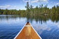 Front of a canoe on a beautiful blue lake with pines and birch on the shore in northern Minnesota Royalty Free Stock Photo