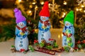 In front of Christmas tree stands milk chocolate snowmans with a sled. Royalty Free Stock Photo