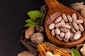 Front close-up of brown herbal pills in a wooden spoon with dry herbs and spices on black background. Herbal drugs concept Royalty Free Stock Photo