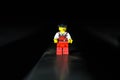 Front closeup Lego movie hero standing on a black surface with dark, blurred background