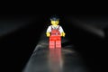 Front closeup Lego movie hero standing on a black surface with dark, blurred background