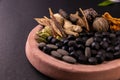 Front closeup shot of black herbal pills, spices and herbs on a grinding stone with black background