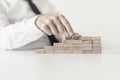 Front closeup view of businessman constructing steps of wooden p Royalty Free Stock Photo