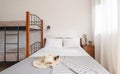 Front closeup view of simple style interior bedroom with classic double bed and bunk bed with metal stairs, wooden furniture on