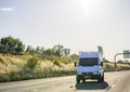 Front of compact cargo business mini van driving in sunshine on the summer road