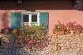 Front of a country house with stacked firewood, window with green shutters and geranium flower boxes Royalty Free Stock Photo