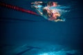 Front crawl. Young woman, professional swimmer in goggles and cap training, swimming in pool indoors. Underwater view Royalty Free Stock Photo