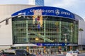 The front of Crypto.com Arena at sunset with people walking on the sidewalk, riding electric scooters and vendors