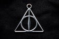 Front Deathly Hallows necklace on a black background of fabric texture Royalty Free Stock Photo