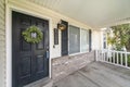 Front door exterior with leaf wreath, wooden white railings and wall bricks