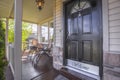 Front door of house with glass panes and porch with chairs railings and columns Royalty Free Stock Photo