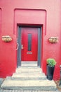 Front door with steps in reykjavik, iceland. House entrance with red door and pot plant decoration. Private property and