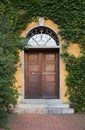 Front door and yellow house facade, overgrown with green ivy leaves Royalty Free Stock Photo