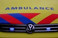 Front of a dutch ambulance in yellow with blue and red striping