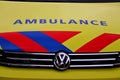 Front of a dutch ambulance in yellow with blue and red striping