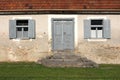 Front entrance to old abandoned house with grass and stone steps in front of wooden doors surrounded with two windows with open Royalty Free Stock Photo