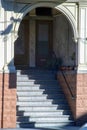 Front entryway or stoop indoors with sunstreak stairs blue and white stucco cement facade with brick on house or home