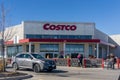 Front facade of Costco hypermarket building with shoppers picking up shopping trolleys