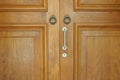 Front facing view of a wooden double doors with small knockers and a handle with lock on the right panel