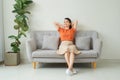 Front full length view tranquil millennial pretty woman relaxing on comfortable sofa in living room