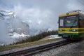 The front of green with yellow hiking train, Jungfrau, with beautiful view of foggy mountain background