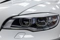 Front headlamp view of white used car stands in the auto showroom sale after washing and polish with orange turn light and led Royalty Free Stock Photo