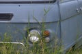 Front and headlight of grayish-blue van abandoned in the field Royalty Free Stock Photo