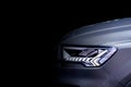 Front headlight with LED xenon light of grey modern EV Car on black colour background