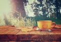 Front image of coffee cup over wooden table and autumn leaves in front of forest background . retro style image Royalty Free Stock Photo