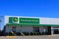 A front of a John Deere Dealership with the building and Advertisement sign with mowers out front