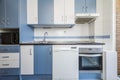 Front of a kitchen with white and blue furniture, built-in appliances, drawers Royalty Free Stock Photo