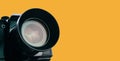 Front lens of vintage film camera with black body isolated on yellow background Royalty Free Stock Photo