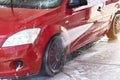 Front light of red car washed in self serve carwash, liquid reflected on side door, high pressure jet water stream spraying on Royalty Free Stock Photo