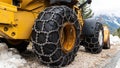 Front loader for snow removal with metal snow chains on wheels. Snow removal in the mountains. Royalty Free Stock Photo