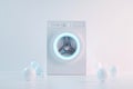 A front-loading washing machine features a vibrant blue circular door, surrounded by soft light particles. The sleek Royalty Free Stock Photo