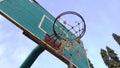 Front and low angle view of dim green old basketball hoop and broken net with a blue background of morning sky in the public sport Royalty Free Stock Photo