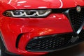 Front mask of first hybrid-powered italian compact crossover SUV car Alfa Romeo Tonale in red colour