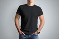 Front mockup black T-shirt on a young guy isolated on a gray ba