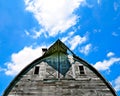 Front of an old abandoned barn sits decaying on an empty farm