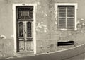 the front of an old abandoned house with shuttered windows and locked wooden door with flaking peeling paint on a sloping street