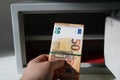 A man holds a stack of fifty euro notes in his hand against the background of an open safe deposit box. Royalty Free Stock Photo