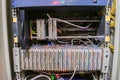 The front panel of a telecommunications cabinet with random interweaving of wires. Communication patch panel for ip telephony.