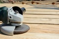 Front part of angle grinder with abrasive disc on planks