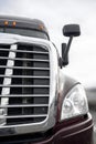 Front part of big rig semi truck with chrome grille and headlight